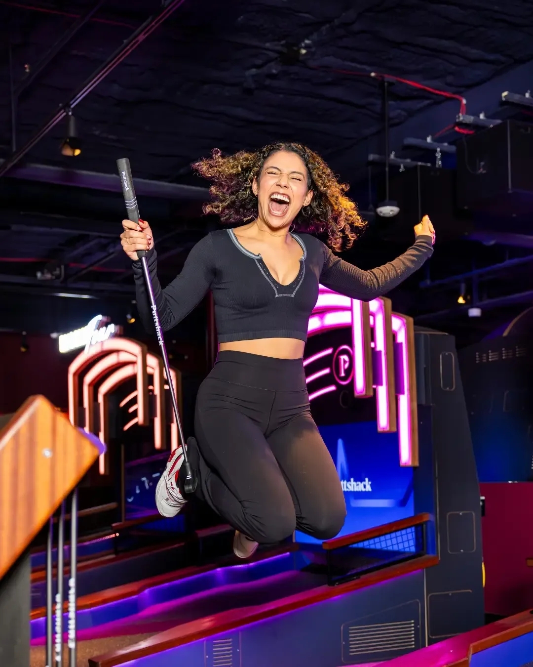 A guest jumping for joy in front of a Challenge Hole at Puttshack