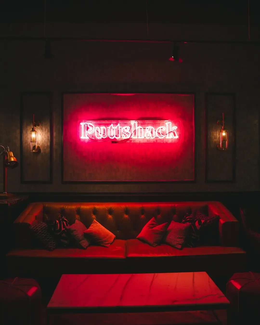 Neon Puttshack sign over a leather couch 