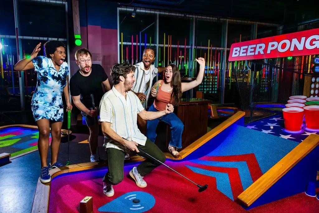 5 people celebrating a shot on a Puttshack course